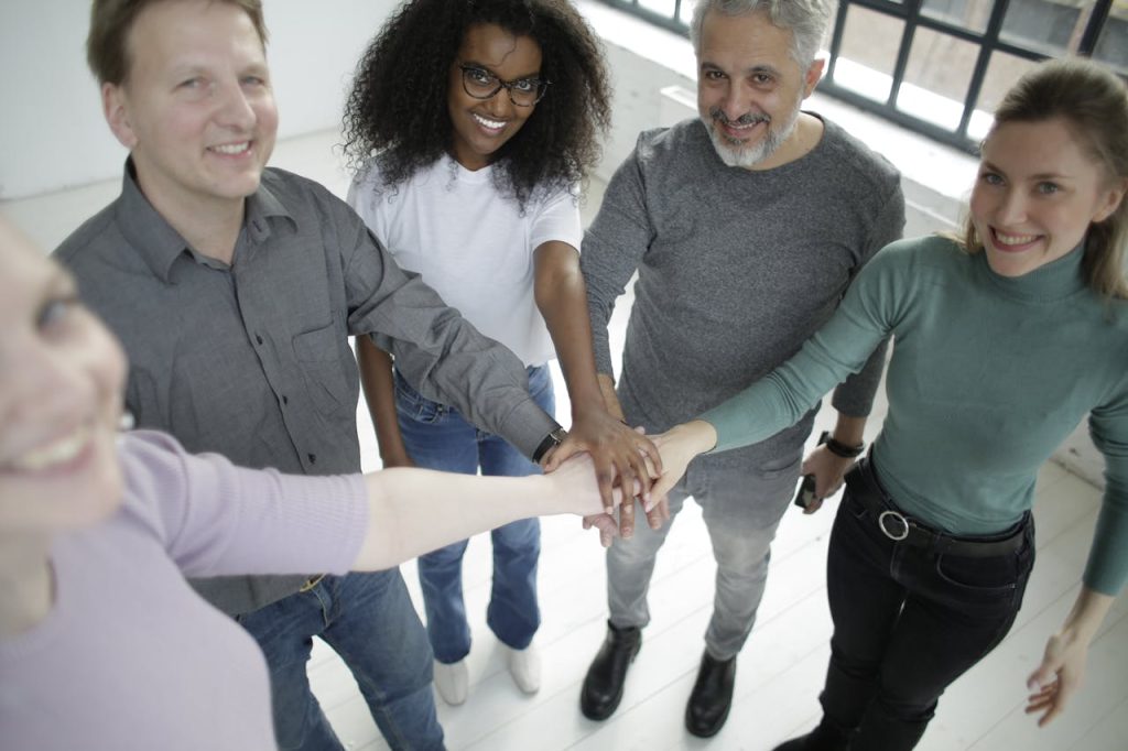 A diverse group of colleagues smiling and stacking hands for teamwork.
