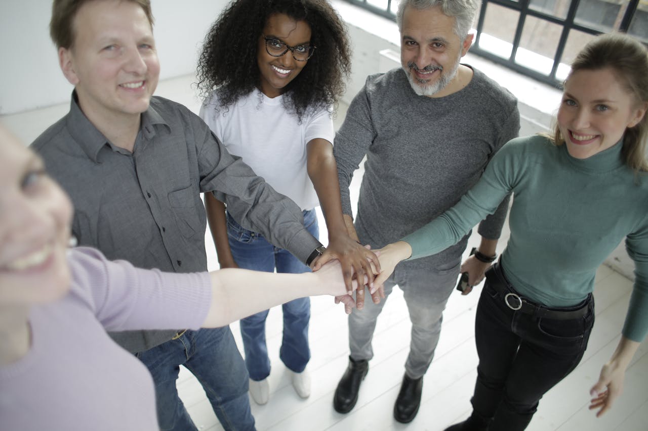 A diverse group of colleagues smiling and stacking hands for teamwork.
